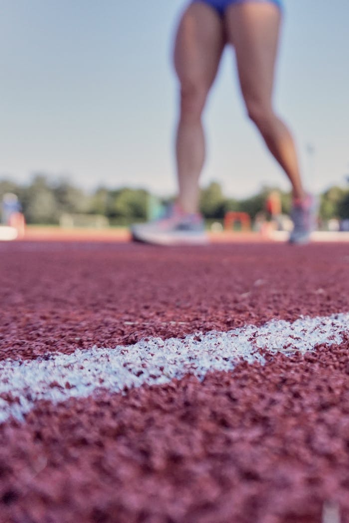 Closeup view of athletes legs standing on outdoor track, perfect for sports-related themes.